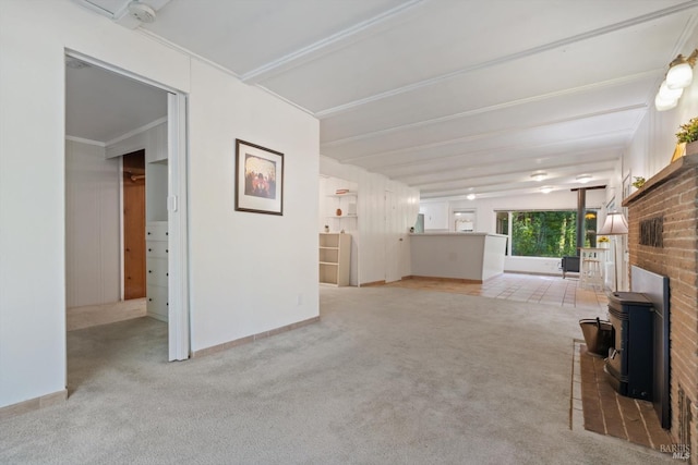 unfurnished living room featuring beam ceiling, a wood stove, carpet, and baseboards