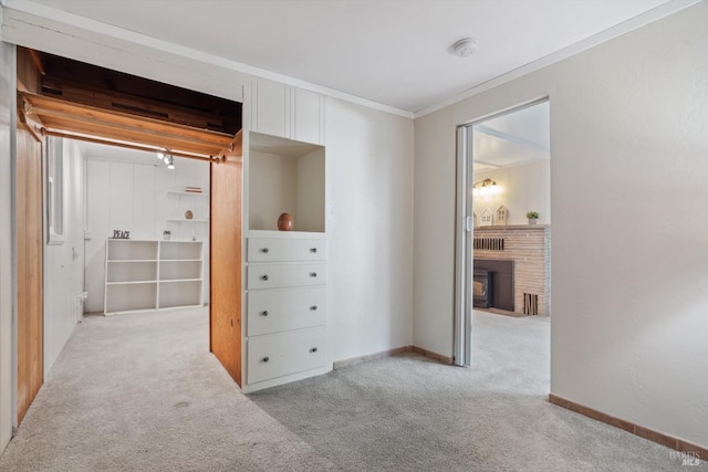 unfurnished bedroom with baseboards, light colored carpet, a brick fireplace, and crown molding