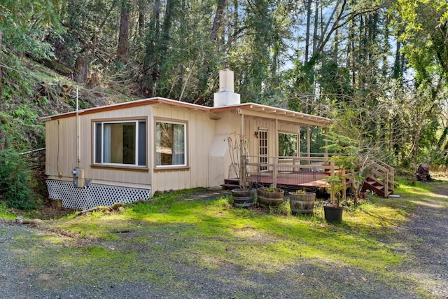 view of front of home featuring a front yard, a deck, and a chimney