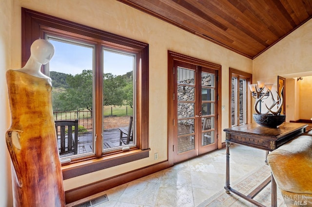 doorway to outside with stone tile floors, visible vents, vaulted ceiling, baseboards, and wood ceiling