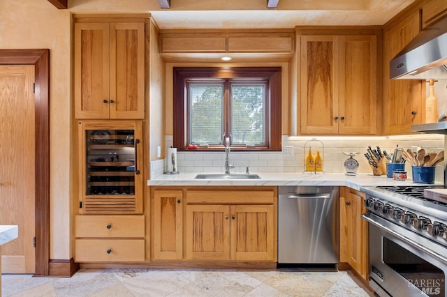 kitchen with exhaust hood, a sink, light countertops, appliances with stainless steel finishes, and beverage cooler