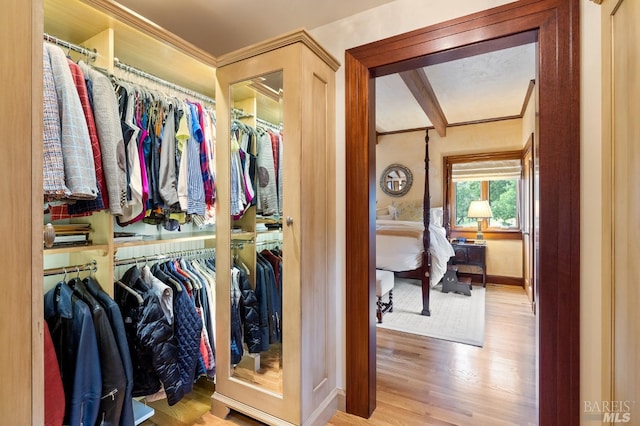 walk in closet featuring wood finished floors and beamed ceiling