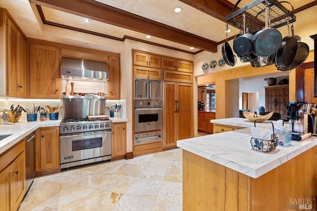 kitchen with brown cabinets, stainless steel appliances, a warming drawer, backsplash, and wall chimney range hood