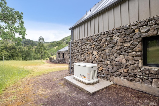 details featuring a power unit, stone siding, and board and batten siding