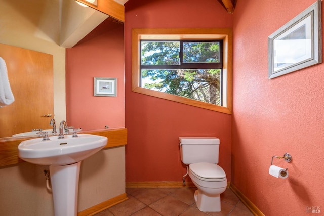 half bathroom featuring toilet, a sink, tile patterned floors, and baseboards