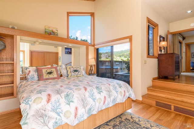 bedroom featuring a high ceiling, wood finished floors, recessed lighting, and access to outside