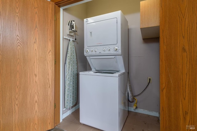 laundry area featuring tile patterned flooring, stacked washing maching and dryer, and laundry area