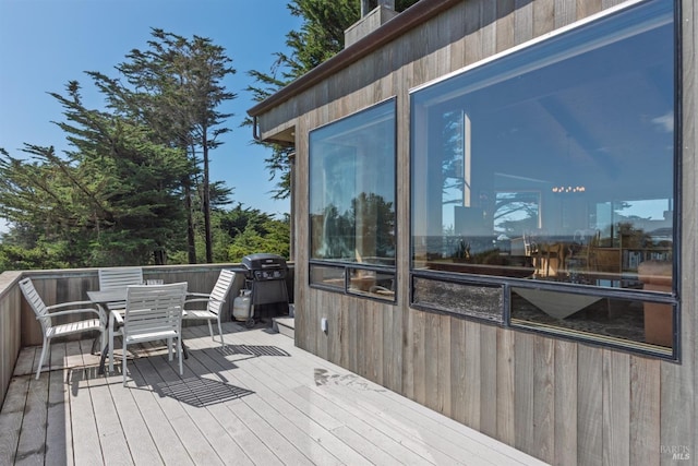 wooden deck featuring a grill and outdoor dining space
