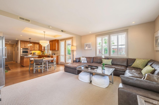 living room with plenty of natural light, visible vents, and light wood-type flooring