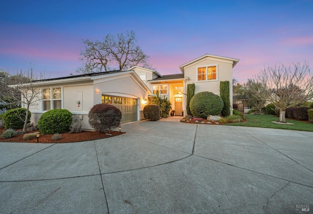 traditional-style home featuring roof mounted solar panels, driveway, a garage, and stucco siding