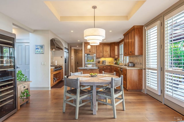 dining space featuring baseboards, light wood-type flooring, a wealth of natural light, and a tray ceiling