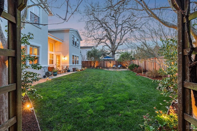 yard at dusk featuring a patio area and a fenced backyard