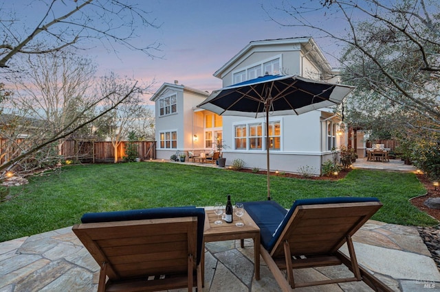 rear view of house with stucco siding, a patio area, and a lawn