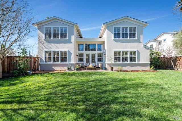 rear view of property with a patio, a yard, stucco siding, and a fenced backyard