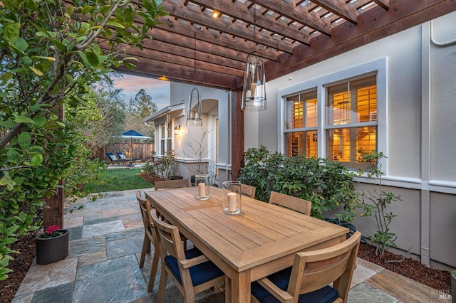 patio terrace at dusk with fence, outdoor dining space, and a pergola
