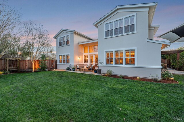 back of house with stucco siding, a yard, a patio, and a fenced backyard