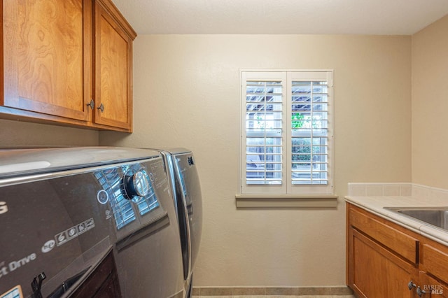 washroom with a sink, separate washer and dryer, cabinet space, and baseboards