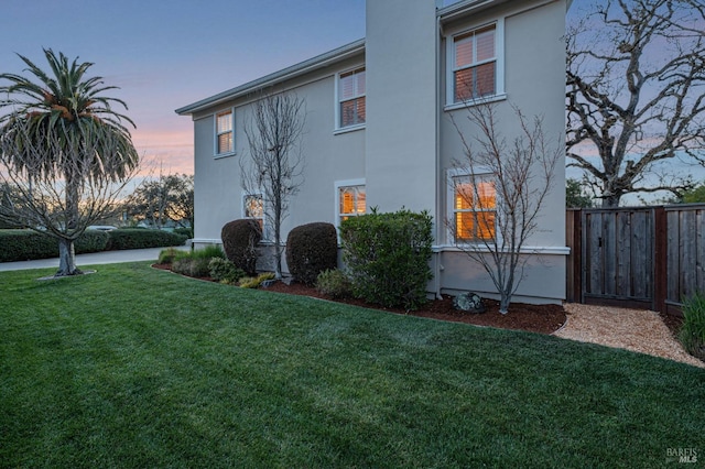 view of property exterior featuring fence, stucco siding, and a yard