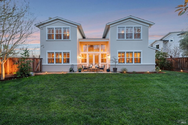 back of house featuring a yard, stucco siding, a fenced backyard, and a patio area