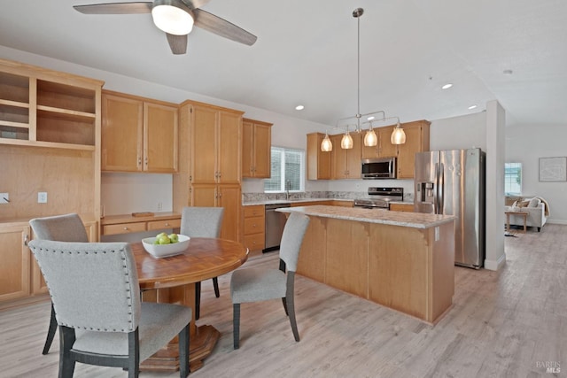 kitchen featuring a ceiling fan, a center island, stainless steel appliances, light wood finished floors, and vaulted ceiling