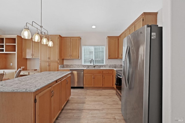 kitchen featuring a kitchen island, pendant lighting, light wood-style flooring, appliances with stainless steel finishes, and a sink