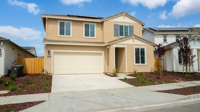 traditional-style house with an attached garage, driveway, roof mounted solar panels, stucco siding, and fence