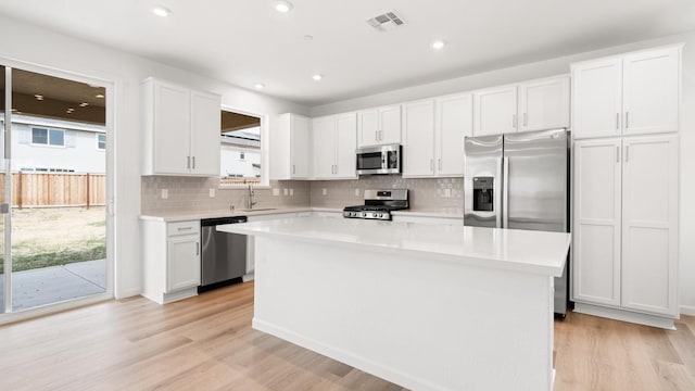 kitchen featuring white cabinets, a kitchen island, appliances with stainless steel finishes, and a healthy amount of sunlight