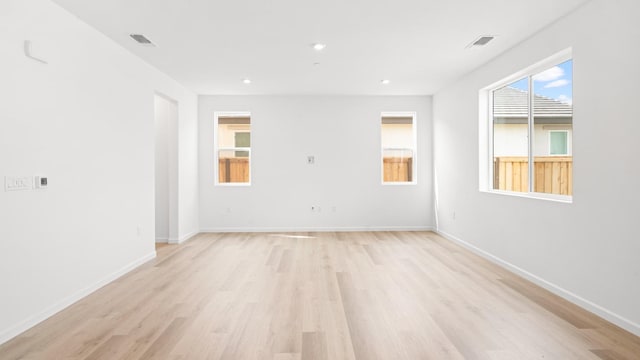 unfurnished room featuring baseboards, visible vents, and light wood-style flooring