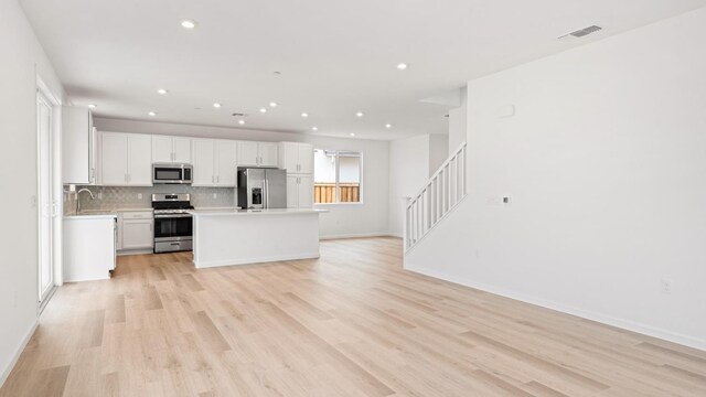 kitchen featuring appliances with stainless steel finishes, light wood-style floors, light countertops, open floor plan, and recessed lighting