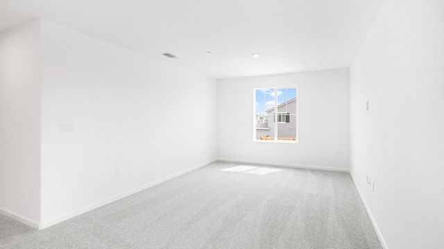 unfurnished room featuring visible vents, light colored carpet, and baseboards