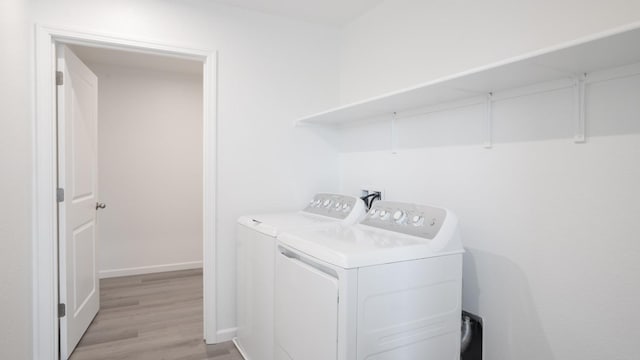 laundry area featuring baseboards, washing machine and clothes dryer, laundry area, and light wood-style floors
