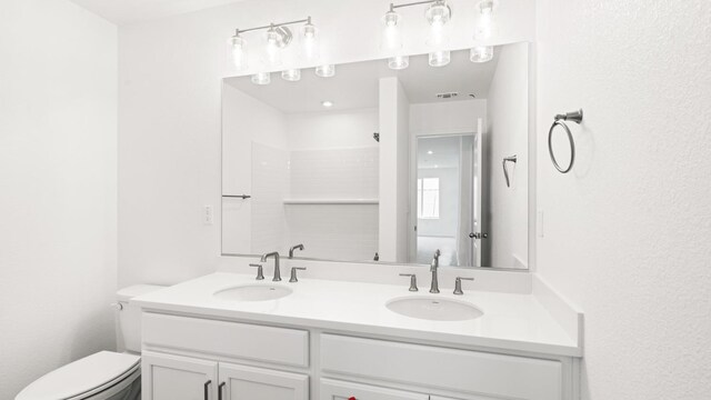 bathroom with toilet, double vanity, and a sink