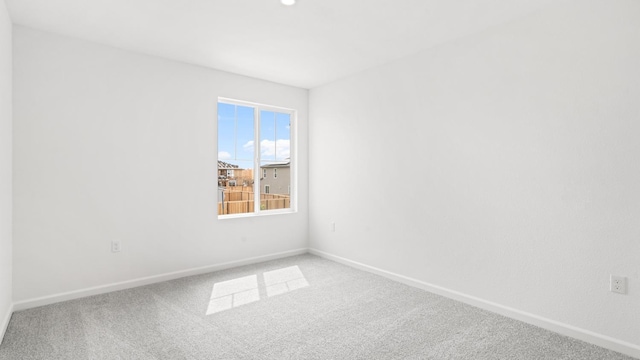 spare room with baseboards and carpet floors