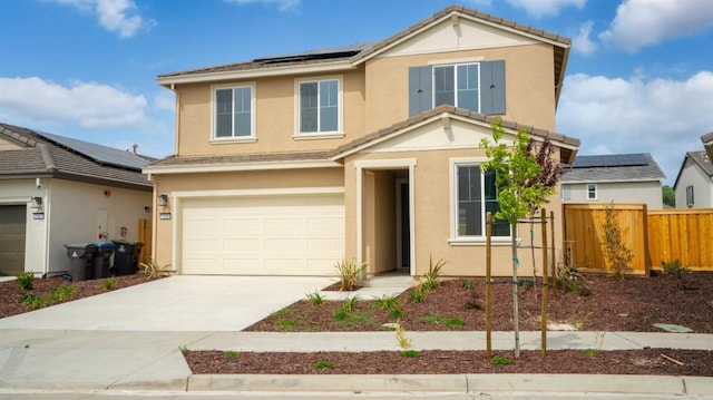 traditional-style house featuring driveway, stucco siding, solar panels, fence, and a garage