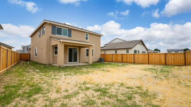 rear view of property featuring stucco siding, central AC unit, a lawn, and a fenced backyard