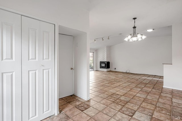 interior space with rail lighting, baseboards, an inviting chandelier, and a fireplace