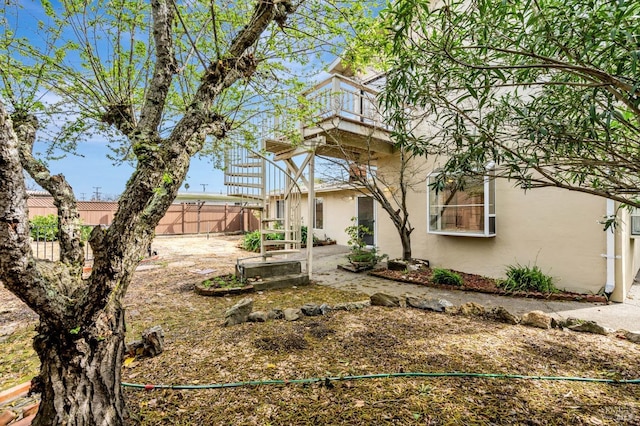 view of yard featuring a patio area, a balcony, and fence
