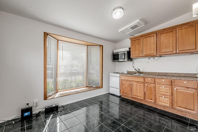 kitchen featuring stainless steel microwave, white range with gas stovetop, vaulted ceiling, brown cabinets, and a sink