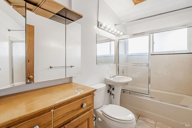 bathroom with tile patterned flooring, toilet, bath / shower combo with glass door, and a sink