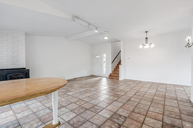 interior space with an inviting chandelier, vaulted ceiling with beams, a fireplace, stairs, and rail lighting