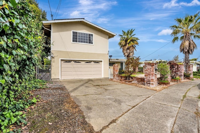 view of front of home featuring concrete driveway, an attached garage, fence, and stucco siding