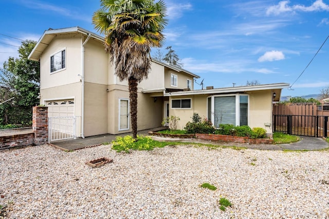 view of front of property with a gate, fence, a garage, and stucco siding