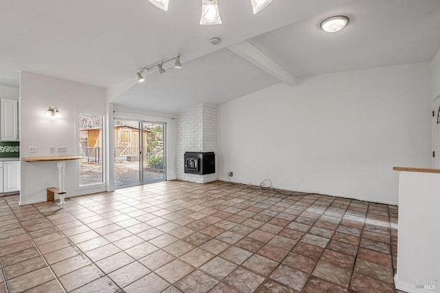 unfurnished living room featuring a fireplace and vaulted ceiling with beams