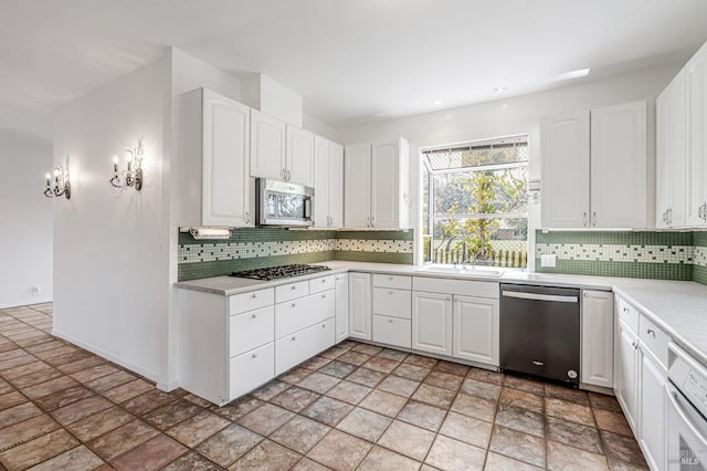 kitchen with a sink, backsplash, appliances with stainless steel finishes, and light countertops