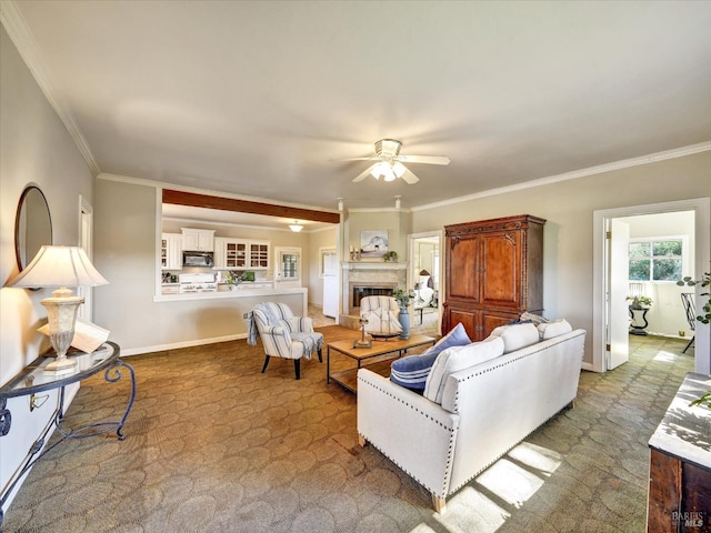 living area with baseboards, carpet floors, a fireplace, ornamental molding, and ceiling fan
