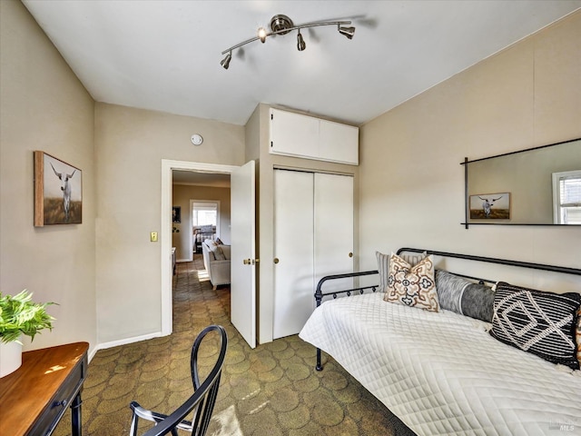 carpeted bedroom featuring a closet and baseboards