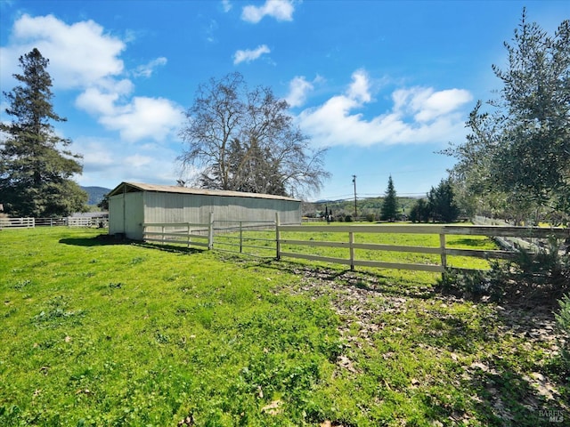 view of yard with a rural view, an outbuilding, fence, and a pole building