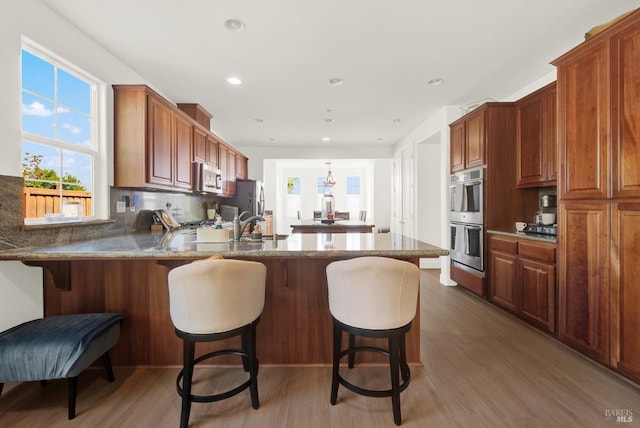 830 Elderberry Loop, Vacaville, CA 95688 - kitchen featuring dark stone counters, decorative backsplash, light wood-style floors, stainless steel appliances, and a peninsula