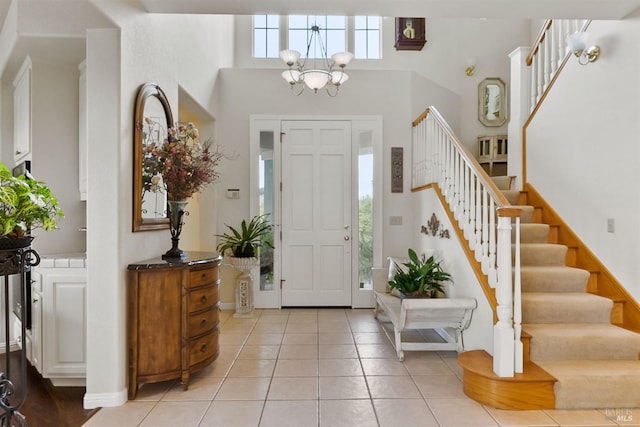foyer entrance featuring a chandelier, stairs, light tile patterned flooring, and a high ceiling