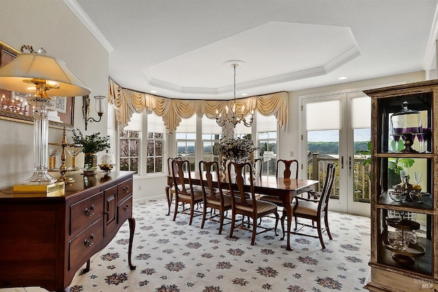 dining area featuring an inviting chandelier, a raised ceiling, light carpet, baseboards, and ornamental molding